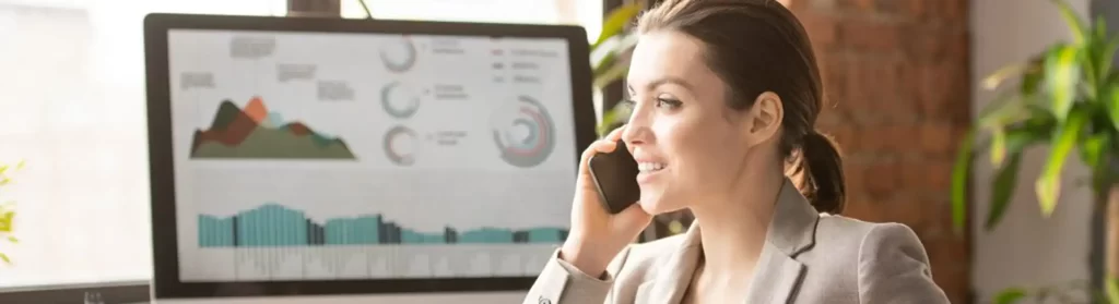 woman on phone siting in front of computer